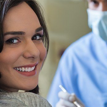 close up of lady with brown hair looking over her shoulder and smiling